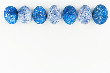 Blue Speckled Easter Egg with copy space for text on white background. Flat lay. Top view