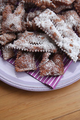Italian carnival pastry on wooden background. Traditional chocolate Crostoli on a plate 