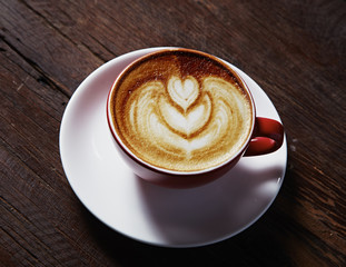Cup of heart latte art on wood table