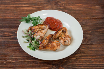 Roasted chiken wings on a plate. Appetizing dish on the wooden brown table.