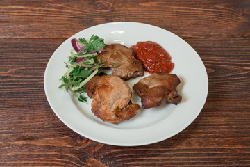 Roasted pork neck on a plate. Appetizing dish on the wooden brown table.
