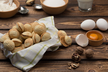 delicious walnut shaped shortbread sandwich cookies filled with sweet condensed milk and chopped pistachio nuts on brown clay dish. on old wooden background, view from above, close-up