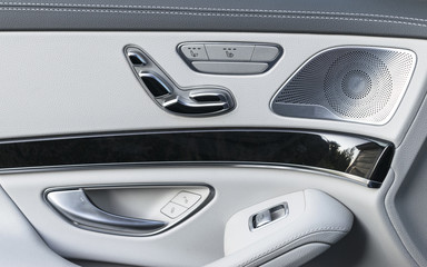 Door handle with Power seat control buttons of a luxury passenger car. White leather interior of the luxury modern car. Modern car interior details