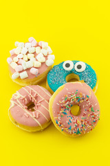 Fototapeta na wymiar Close-up with many multicolored glazed donuts on yellow background.
