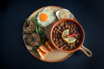 A high angle view/color studio image of Egyptian, Arabian, Middle Eastern Traditional food (Fava Beans with Lemon and Chili Red Paprika and with Falafel, Tomato and Fried Egg aside) A.K.A (Foul and Fa