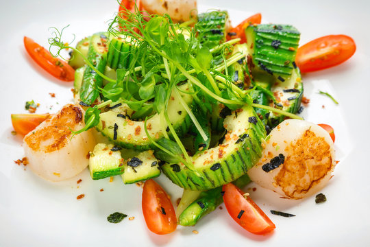 salad of zucchini with scallops and tomatoes on a white plate in a restaurant