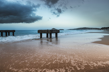 Molo romano a Spiaggia di Campana Dune all'alba con temporale all'orizzonte