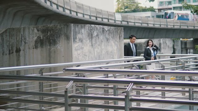 Two Asian colleagues were walking up stairs on metro station