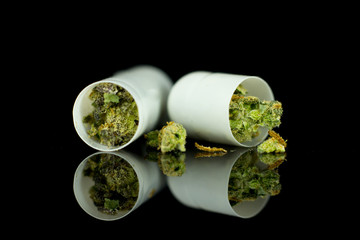 Medical Pills and tablets Cannabis - marijuana flowers inside pills on the mirroring black background.