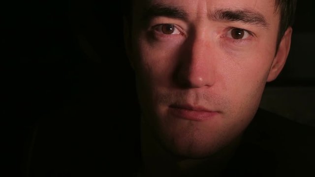 Young man's face in the dark. Closeup shot.