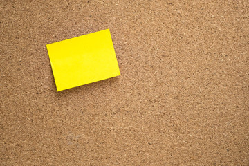Fototapeta premium yellow sticky note pasted on brown cork board with copy space