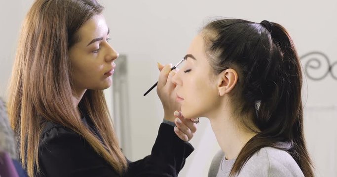 Close up of visagist doing make-up, coloring eyebrows with mascara