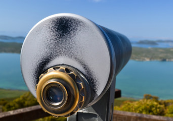 Touristic telescope look at the Vransko lake and Dalmatian islands in Croatia, close up metal binoculars view and blue sky.