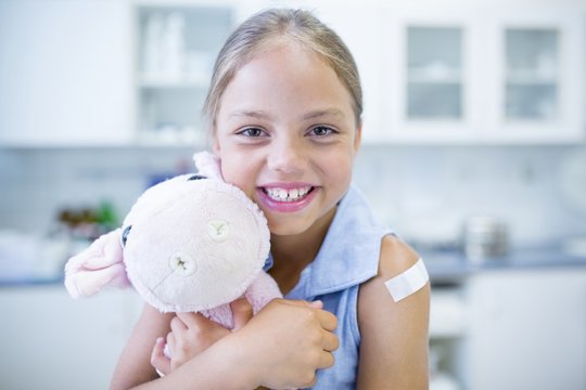 Girl with plaster on arm hugging teddy