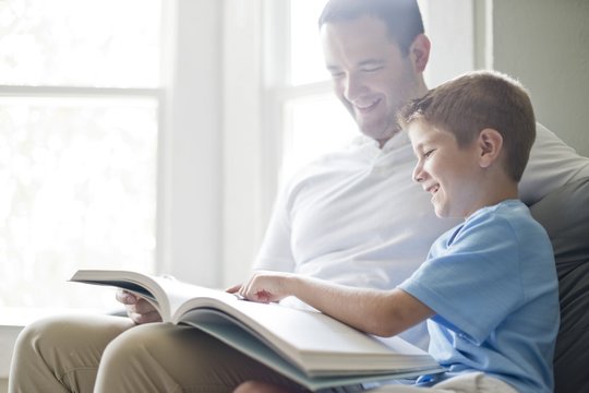 Boy reading book with his father