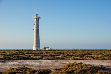Fototapeta na wymiar Lighthouse on Morro Jable beach on Jandia peninsula in sunrise light, Fuerteventura, Canary Islands, Spain
