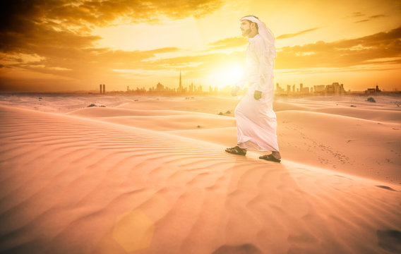Arabic man with traditional emirates clothes walking in the desert