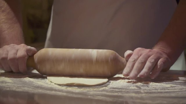 Making pizza or pide dough by close up male hands in pastry kitchen. Shaping dough is precursor to making a wide variety of food stuffs, particularly breads, biscuits, cakes, cookies, dumplings, pasta