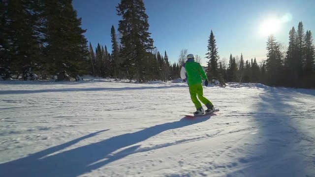 Sportsman moves down on extreme snowboard upon a slope of the mountain at winter sunny day