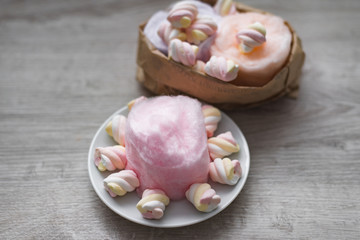 Composition of orange, rose and violet sweet cotton wool and a colorful souffle on a wooden background. Sweet fun for children and their parents. Culinary delights