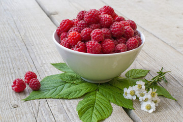 full bowl of juicy ripe raspberries, decorated with chamomile flowers matricaria, perfect colorful...