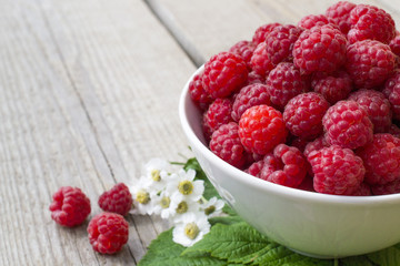 full bowl of juicy ripe raspberries, decorated with chamomile flowers matricaria, perfect colorful...