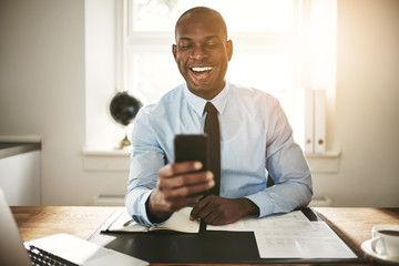 Smiling young businessman laughing at a cellphone message