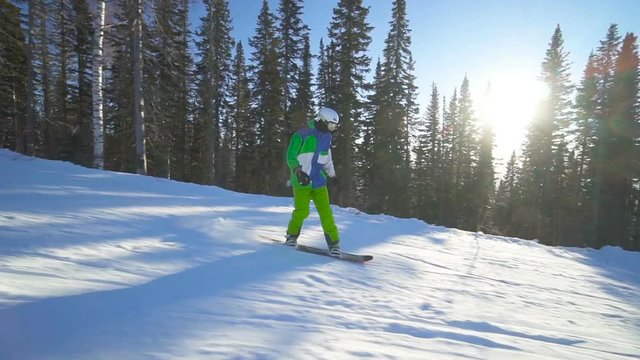 Sportsman moves on extreme snowboard upon a slope of the mountain at winter sunny day
