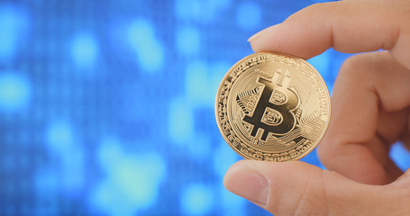 Hand holding bitcoin over digital abstract background