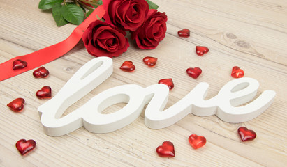 
Red roses with hearts and the lettering love on wooden table, Valentines Day background, wedding day