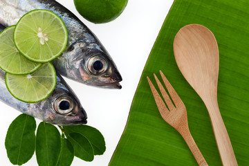 Fresh fish with lemon and wooden spoon on banana leaves background,concept cooking background.