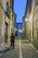 Night view of a narrow cobblestone alley with facades of 16th century houses called Santa Maria next to the Plaza de Cervantes in Alcala de Henares (Spain)