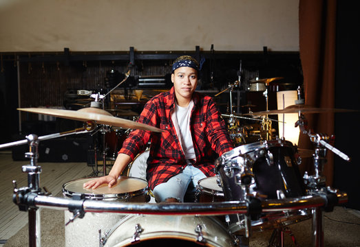 Young Contemporary Drummer Sitting In Studio Or Garage In Front Of Drum Set