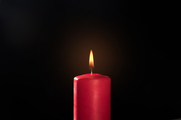 burning red candle on a black background