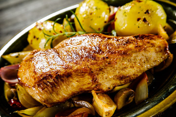Roast chicken breast with potatoes on wooden background