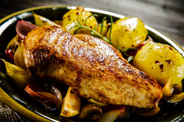 Roast chicken breast with potatoes on wooden background