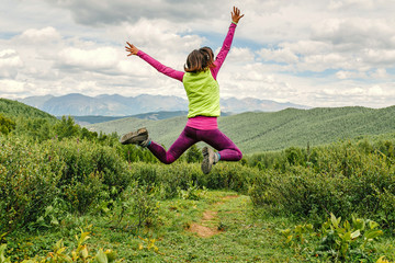 young woman jumping on meadow in mountains