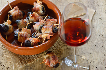Leckere Tapas: Getrocknete Pflaumen in Speck gerollt und gebraten, dazu ein Glas Old Tawny Portwein – Delicious Spanish tapas:  Fried prunes wrapped in bacon served with Portuguese port wine