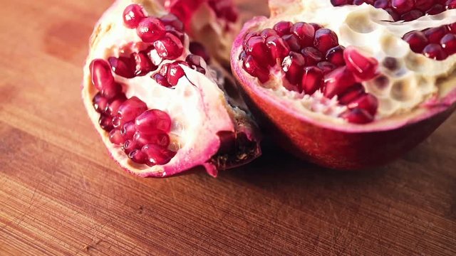 Pomegranate seeds on bamboo board close-up shot. Smooth rotation.