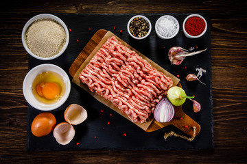Raw minced pork on cutting board and vegetables