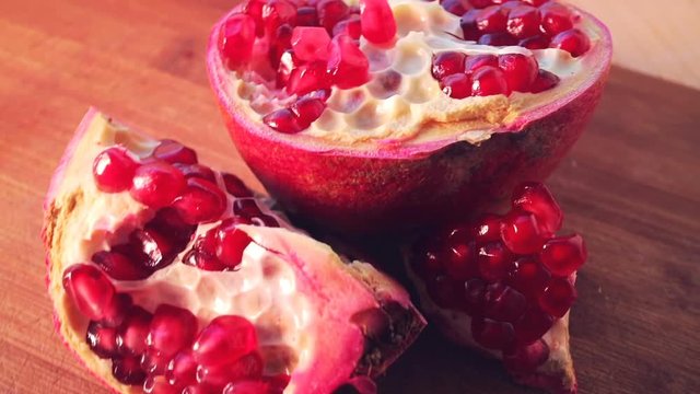 Pomegranate seeds on bamboo board close-up shot. Smooth rotation.