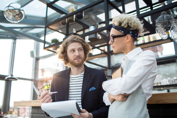 Young confident revision manager or owner of cafe having talk to new waitress at the beginning of...
