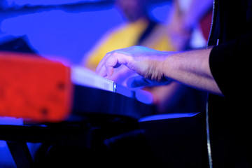 A musician on an electric piano plays live music at a concert in an orchestra