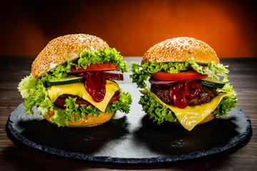Two tasty burgers with cheese and ketchup served on black stone