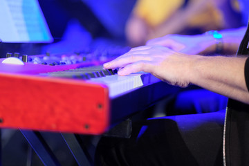 A musician on an electric piano plays live music at a concert in an orchestra