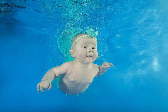 A little girl in a mermaid costume swims underwater