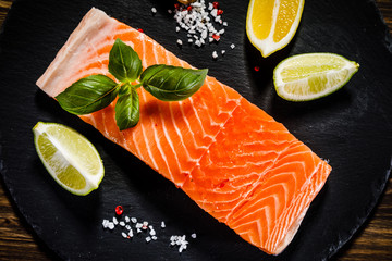 Fresh raw salmon fish served on black stone on wooden table