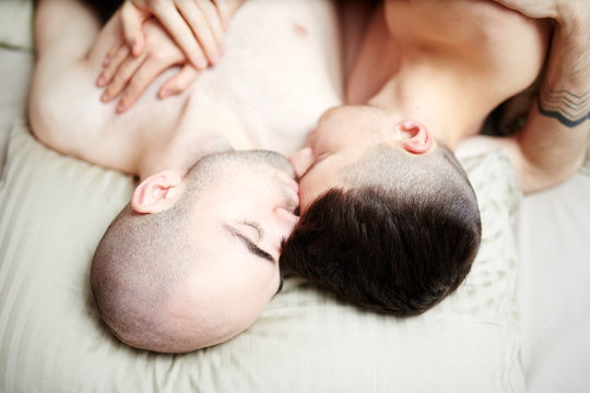 Young amorous homosexual men sleeping together on one pillow
