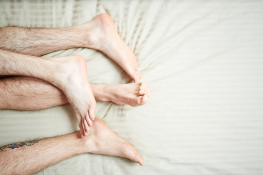 Feet and hairy legs of homosexual couple during sleep in bed