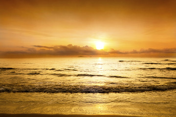 Obraz premium Sunset in the twilight time with sky yellow and orange color over the sea slowly waves at the tropical beach.